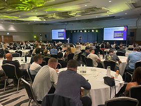 Zoe Thompson, coach, speaking to a room full of people at a company conference