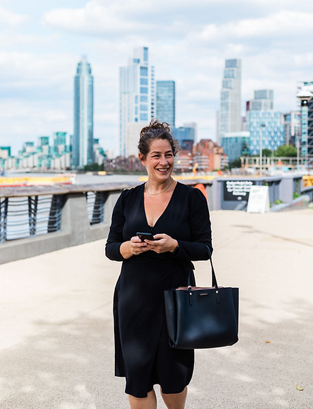 Zoe Thompson - white female, brown hair, black dress walking along the Thames in London
