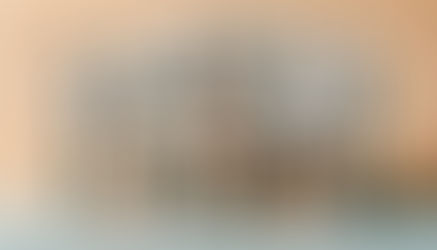 origami people in a work environment - 6 figures standing behind a figure sitting at the table witha head in their hands, laptop open and piles of paperwork - clocks surround the image suggesting time pressure