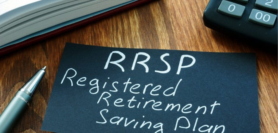 A hand-written sign with RRSP - Registered Retirement Savings Plan and a pen resting on a desk.