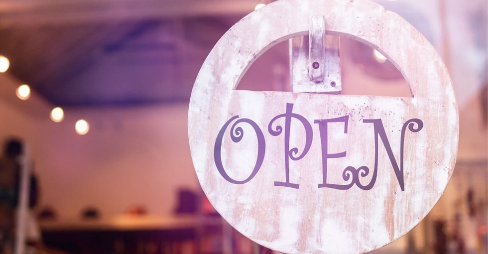 A Round "Open Sign" hanging on a business window.