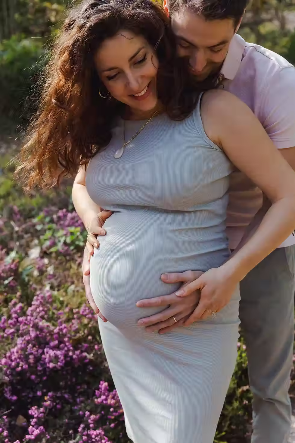 Photo gros plan d'un couple lors d'une séance photo grossesse tenant tendrement le ventre de la future maman