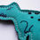 Thumbnail: A green T-Rex shaped dog toy layed on grass with black stitched detailing
