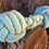 Thumbnail: A blue and natural rope tug toy for dogs, two monkey knots with a plaited centre against a sand stone back drop