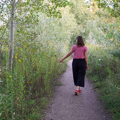 eine Frau geht entspannt einen Weg entlang