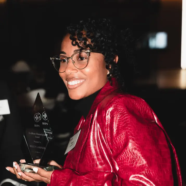 Smiling woman in red jacket holding award