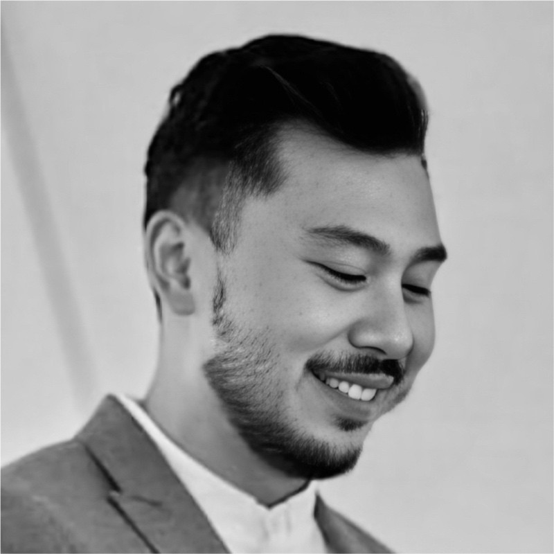 Man looking down to the right wearing a suit and a white shirt, greyscale picture