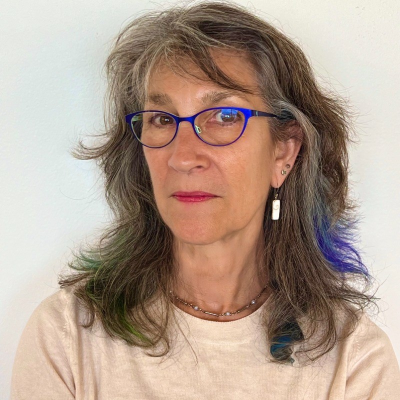 Woman with long hair and glasses wearing a white shirt