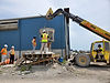 Workers at UHPC site using a telehandler to lift equipment.