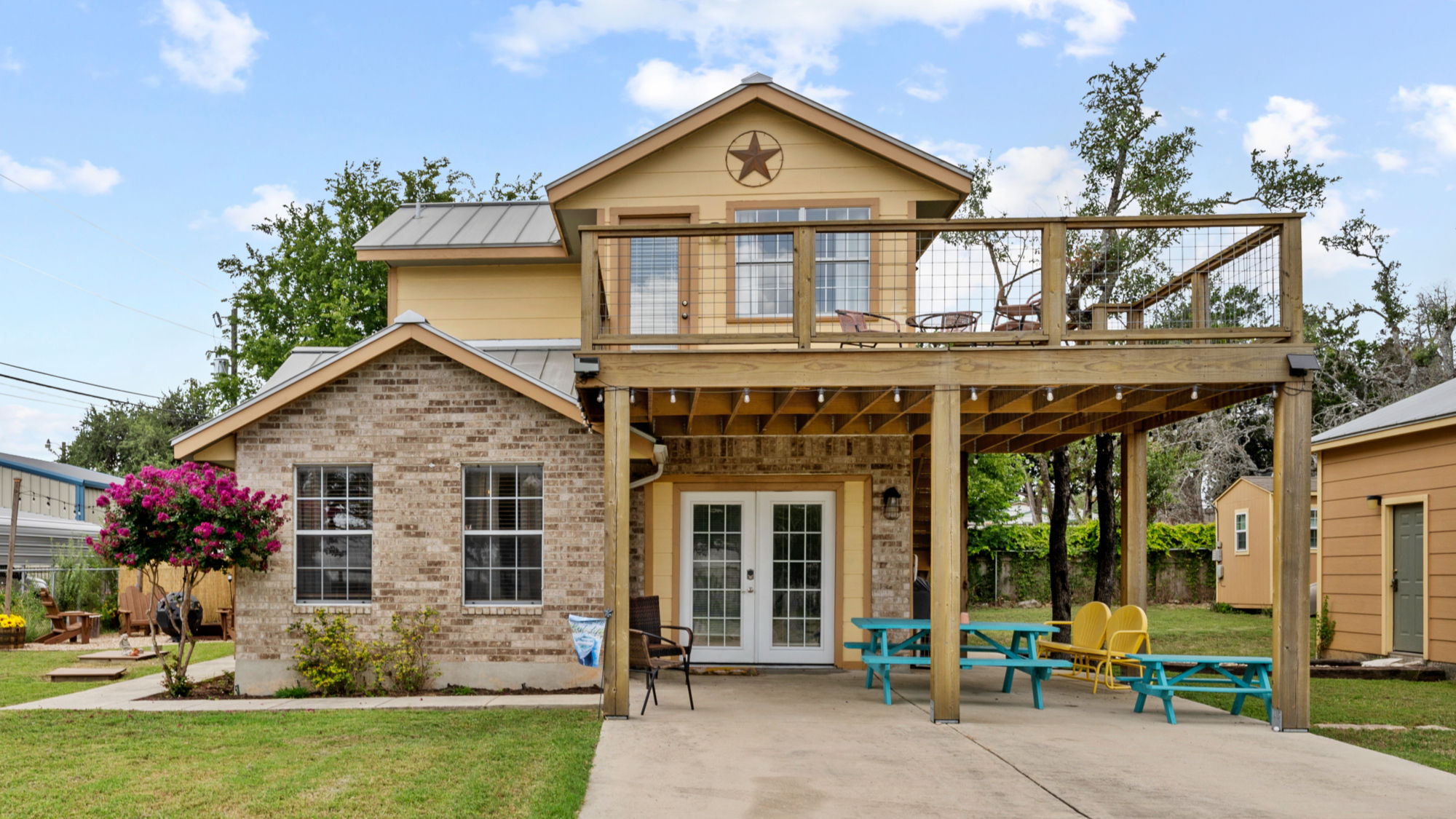 Yellow house with stone base, wooden deck, and outdoor seating