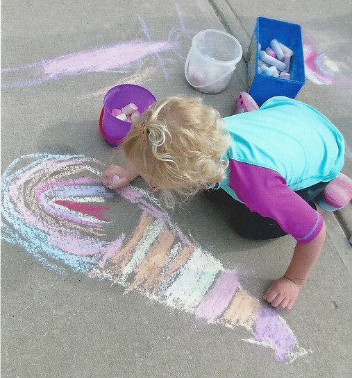 Girl drawing with chalk on sidewalk