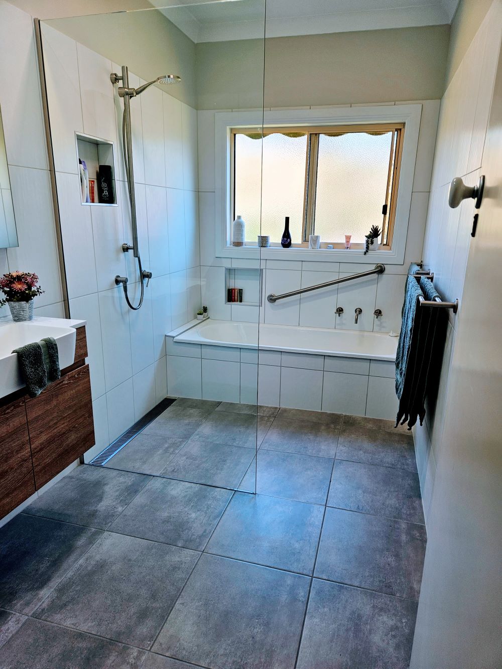 A bathroom renovation including modifications suitable for independent living for NDIS participants and elderly including a walk in shower and grab rails.