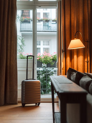 Apartament Classic w Agapella Sopot — elegancki pokój z walizką, balkon z widokiem na kamienicę, drewniane wnętrze, apartamenty Sopot
