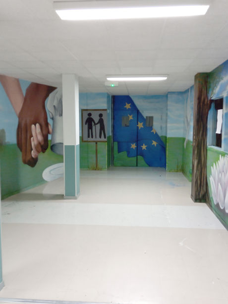 Couloir d'école avec peintures murales colorées et décoratives, ambiance ludique et accueillante