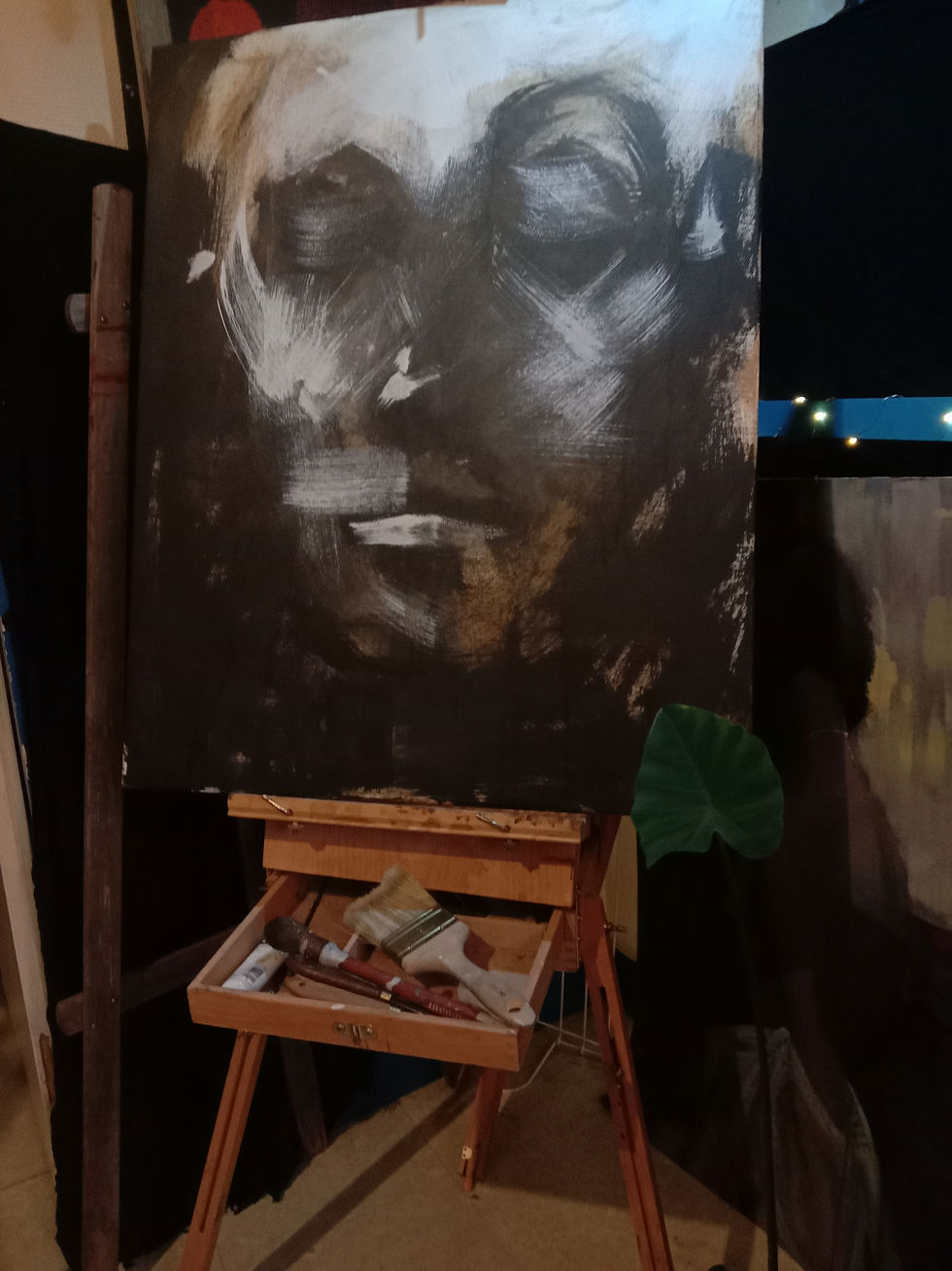 Peinture en noir et blanc d'un visage, avec un chevalet et des pinceaux.