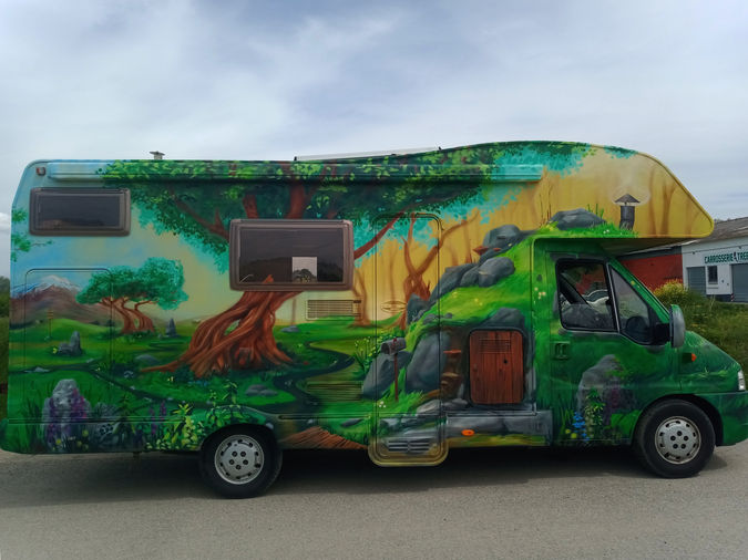 Graffiti sur camping-car illustrant une forêt féerique et une petite maison style Hobbit.