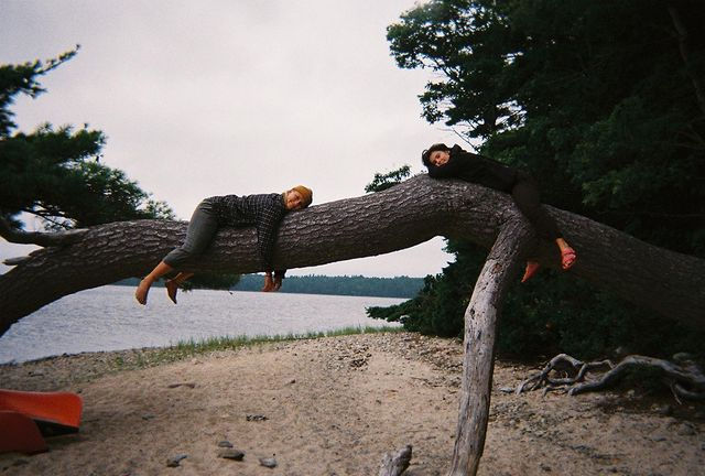 two people camping relaxing on fallen tree