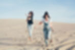 two female friends running on beach laughing