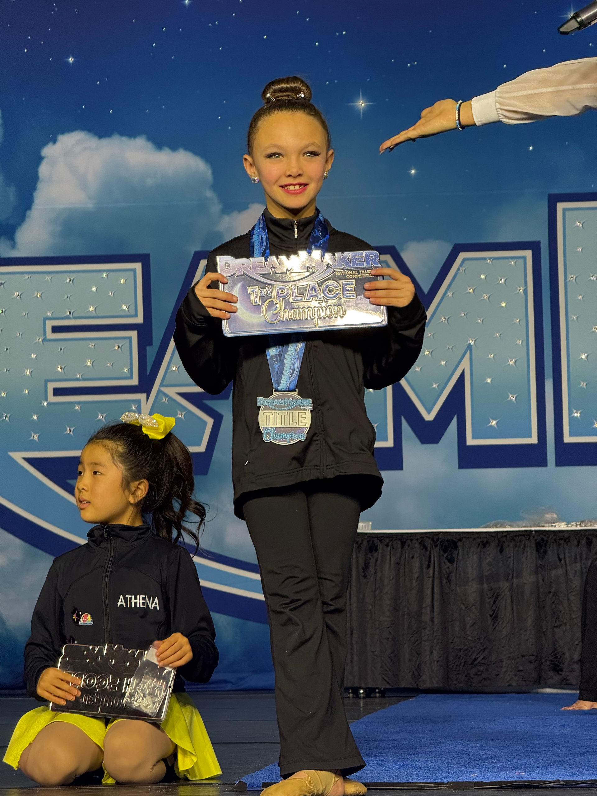 Young girl holding award, wearing medal during a dance competition Athena.