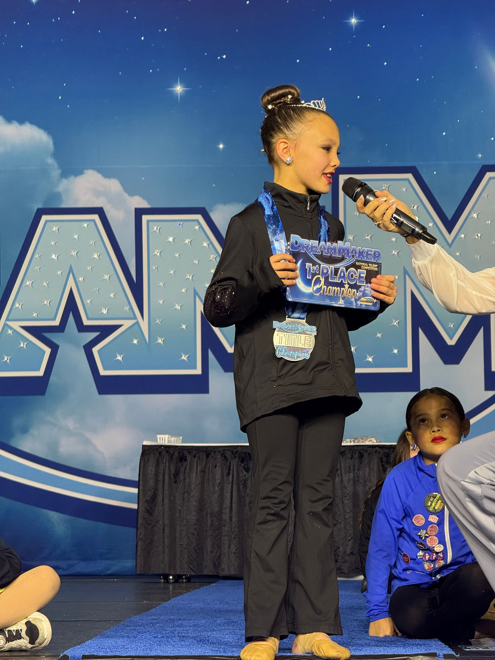 Young girl holding award on stage with microphone and 