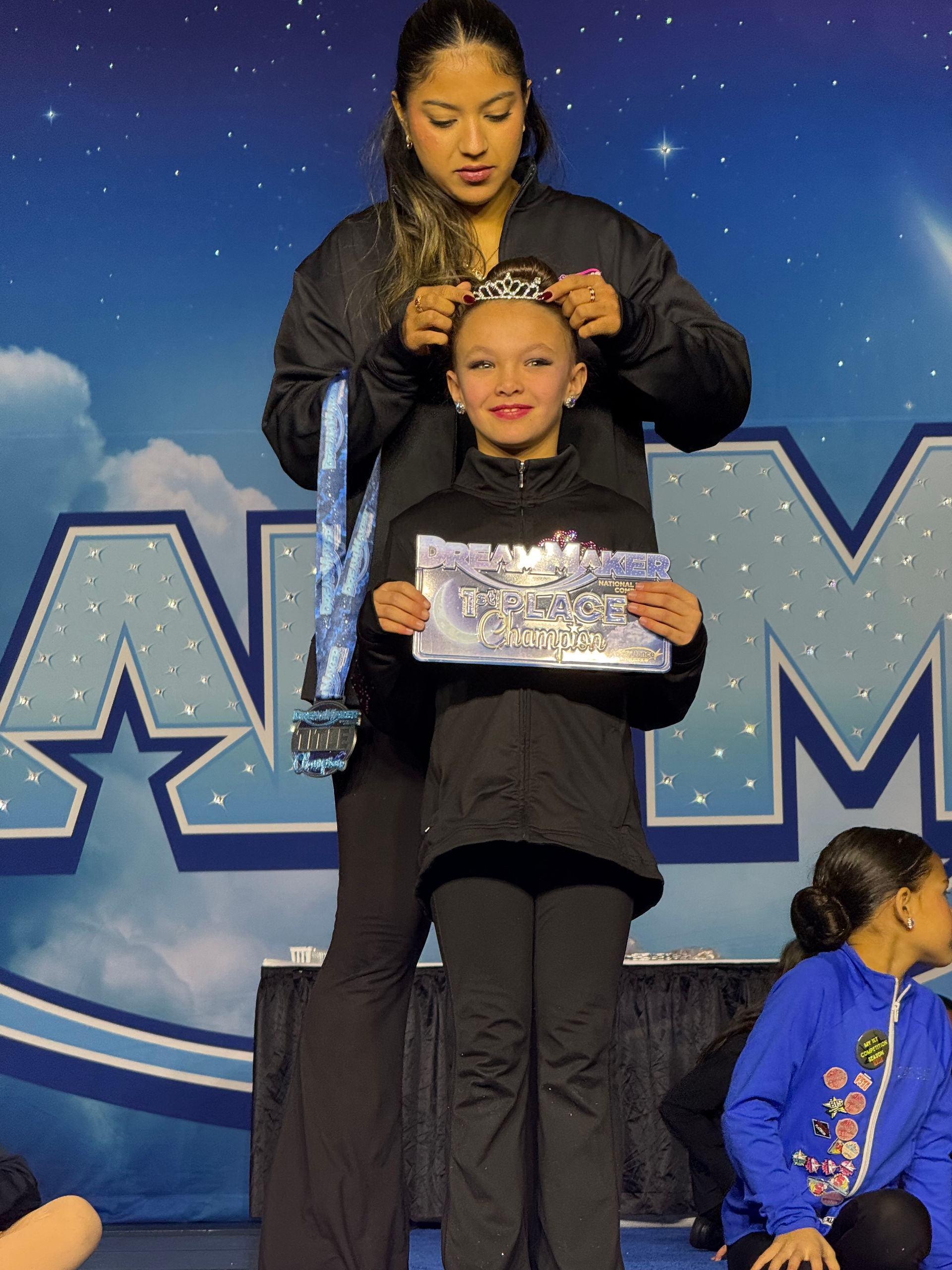 Young dancer receives award on stage, smiling with the text Dream Dance