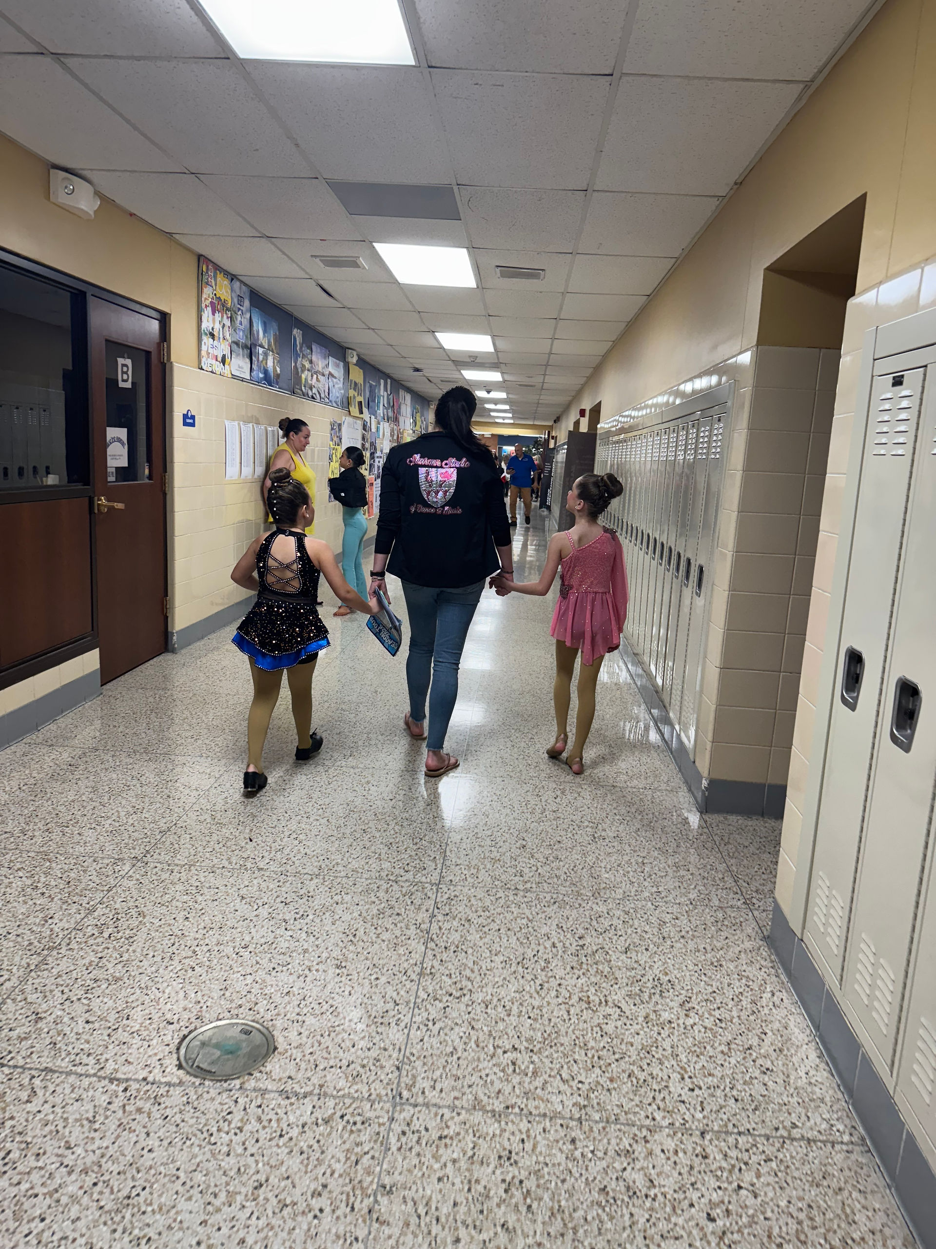 Dancers walk down hall, holding hands. Dancer's Inc. 2025. Preparing for dance competition.