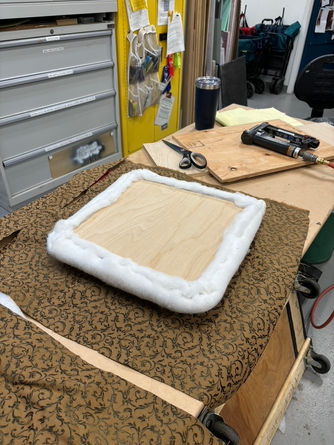 Reinforcing the chair structure with a plywood base before securing the foam, batting, and final fabric.