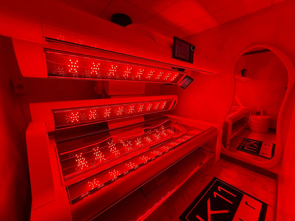 Red-lit room with a tanning bed featuring bright lights and displays. Reflective surfaces and patterned rugs create a futuristic ambiance.