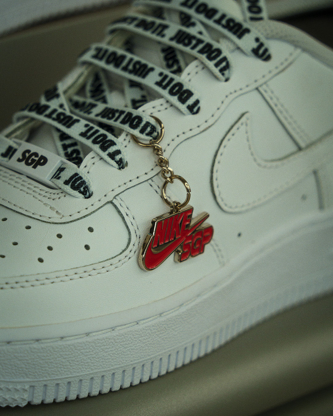 red NIKE SGP charm on lace of a white sneaker singapore
