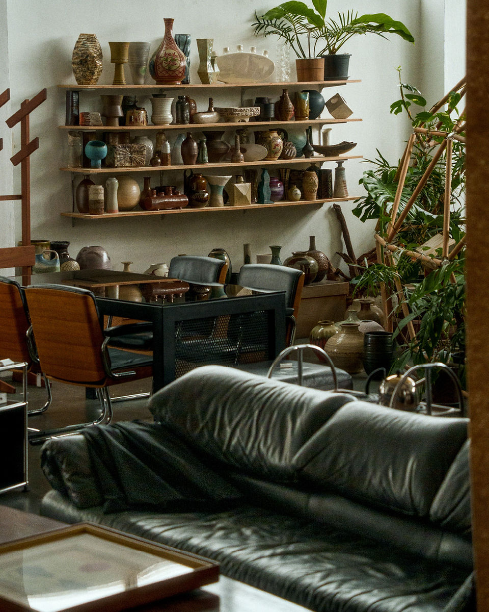 couch and furniture in wood-rich and plant-rich store, beautiful pottery lines shelves in background