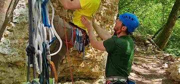 grimpeur débutant progressant en falaise avec moniteur d’escalade nature en petit groupe