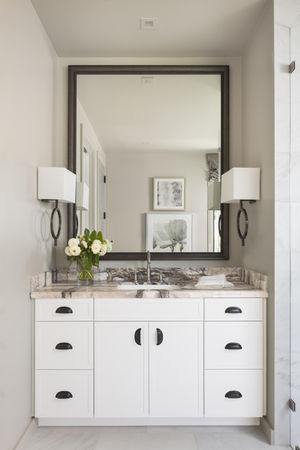 White vanity with mirror and lamps in a modern bathroom.