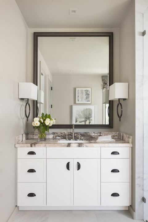 White vanity with mirror and lamps in a modern bathroom.