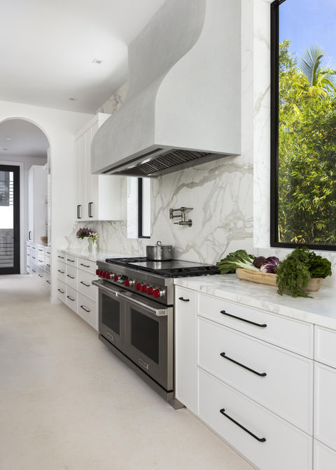 Modern kitchen with white cabinets, stainless steel appliances, and marble backsplash.