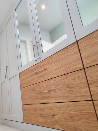 Matthew Kirk Interiors handmade bespoke dressing room. Shaker styled doors with inset mirrors painted in Fired Earth paints. Book matched oak veneered drawers finished with steel bar handles and solid oak work surfaces. Installed in Linton, Wetherby, West Yorkshire