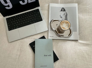The Social Inclusive laptop on beige couch with magazine and chrome coffee cup sitting ontop of it