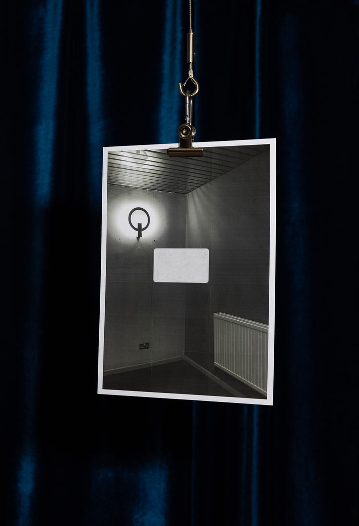 Black and white printer labels containing a interior scene of offices, the print is hung up with a bulldog clip against a blue velvet background
