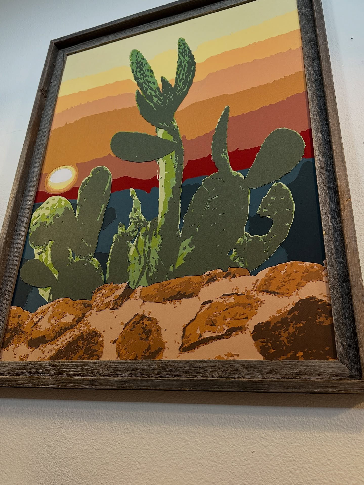 a framed painting of a cactus in the desert
