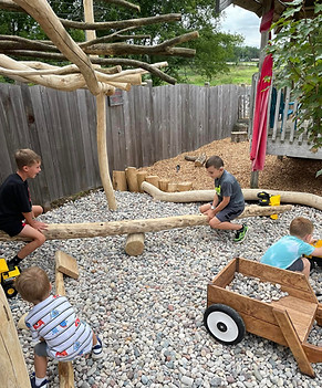 making a teeter totter with logs and digging in a dry rock bed on messiah lutheran Preschool in Wauconda