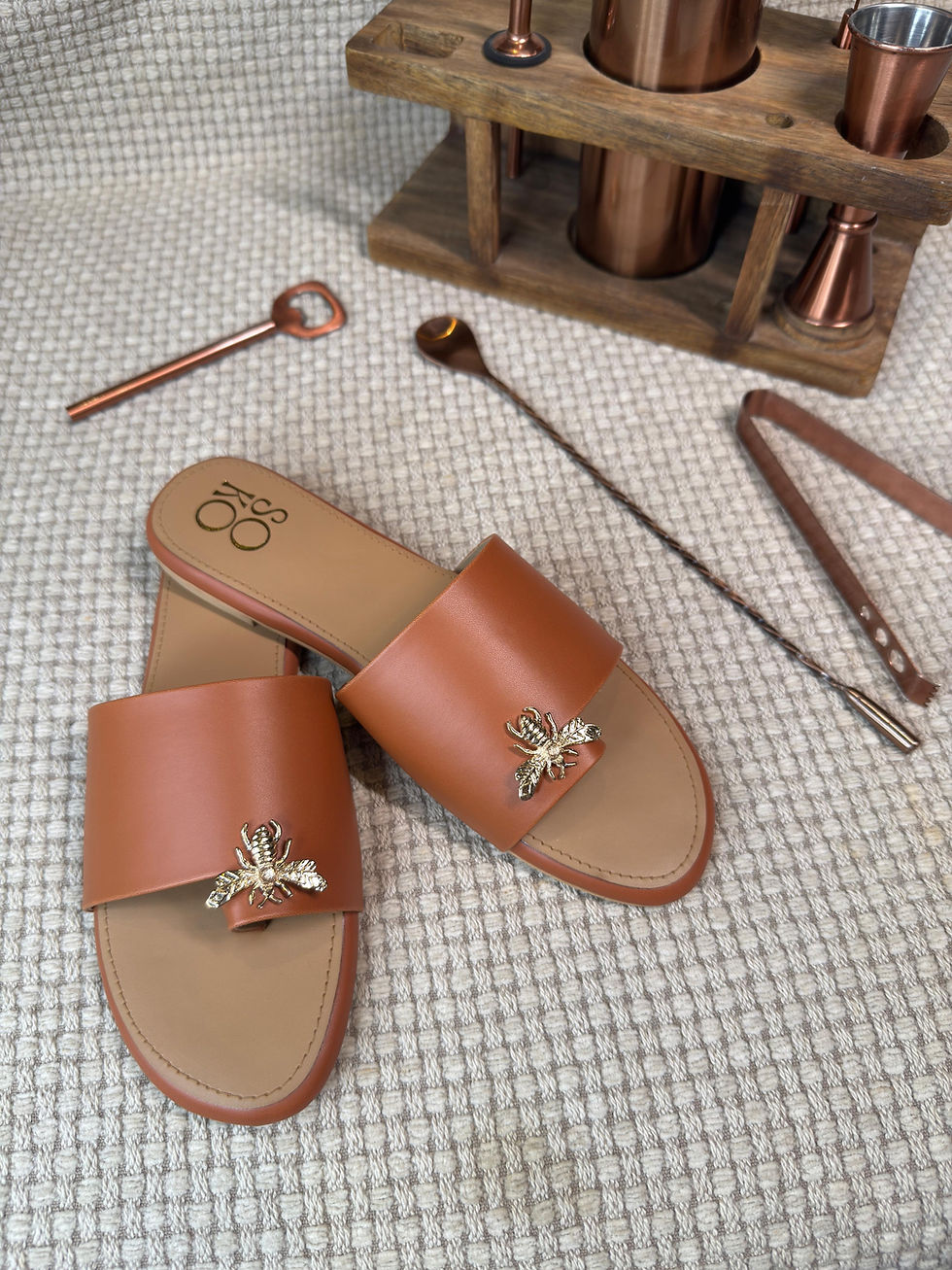 Pair of brown leather sandals with cocktail bar tools on display