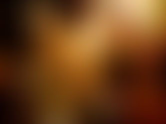 A child in warm clothes sits by a grave adorned with marigolds and candles, among standing people, in a dimly lit cemetery on the Day of the Dead. 