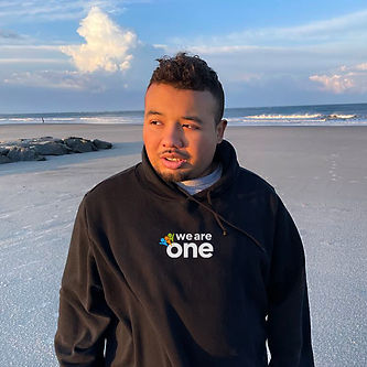 25 year old African American man standing on the beach in a black We Are One Foundation sweatshirt
