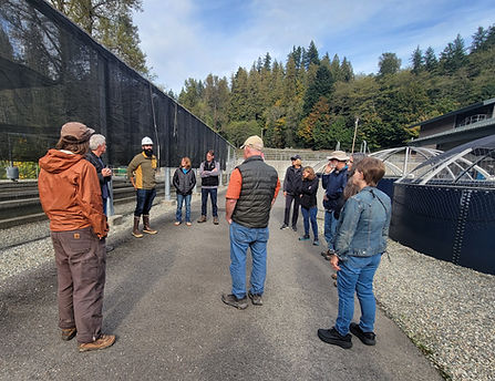 A group of people at the Baker Dam hatchery between several types of fry holding tanks.