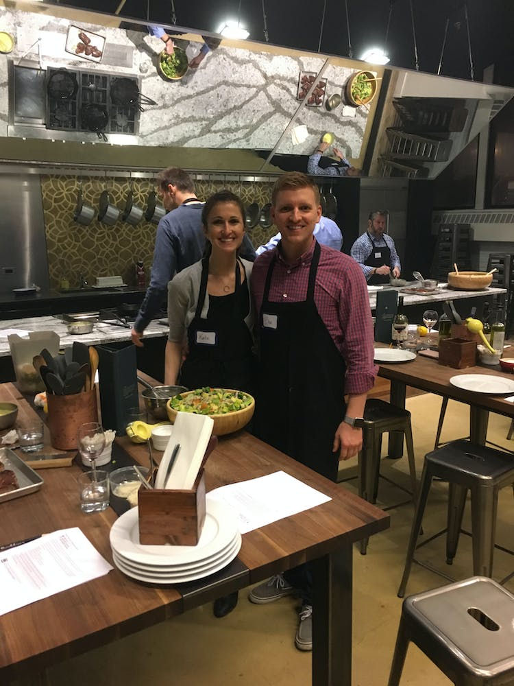 a man and women in a cooking with a large bowl of salad in front of them