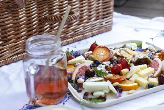 a glass of tea in a clear mason jar next to a charcuterie board