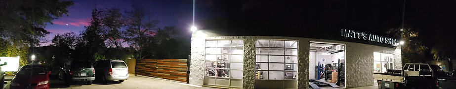 Street view of automotive repair shop with a modern, horizontal slat gate, in Garner, NC at dawn.