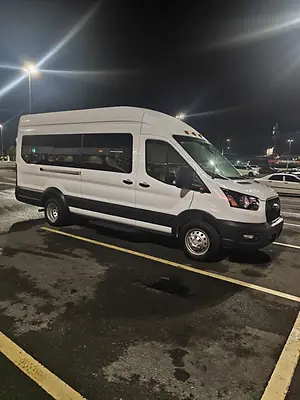 White Ford Transit passenger van parked at night