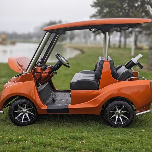 Orange golf cart parked on grass near a lake. Golf Cart Dealer
