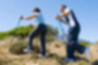 Two hikers using Nordic walking sticks while going up a hill to reduce the strain on their injured Achilles tendons.