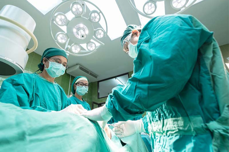 A surgeon and nurses in an operating theatre.